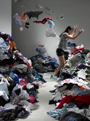 Woman throwing clothes in overflowing laundry room
