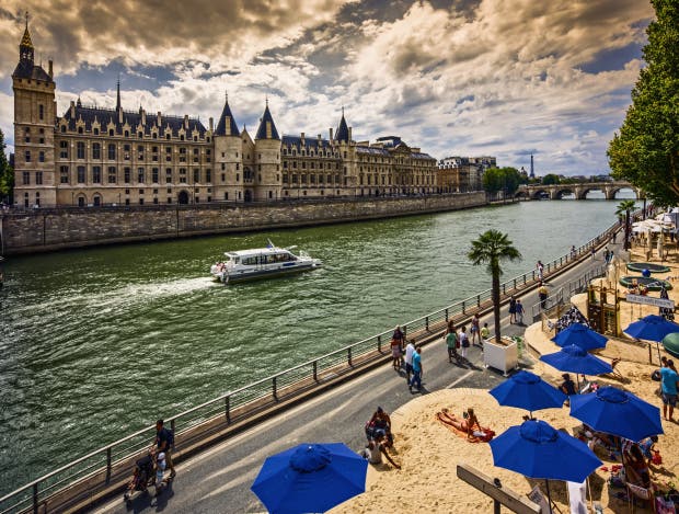 People enjoy the sun during 'Paris-Plages' on quays of Seine river, 'Conciergerie', 'Pont Neuf' bridge, Eiffel Tower, Paris, France