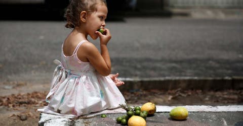 Unos niños venezolanos engañan el hambre con frutas podridas desechadas en un mercado