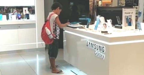 La emotiva imagen de un niño usando una tableta en una tienda para poder hacer sus deberes
