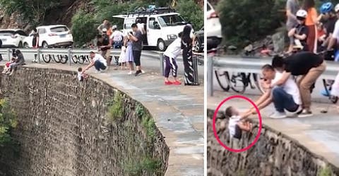 Graban a un padre colgando a su hijo pequeño de un alcantilado para tomarle la foto perfecta