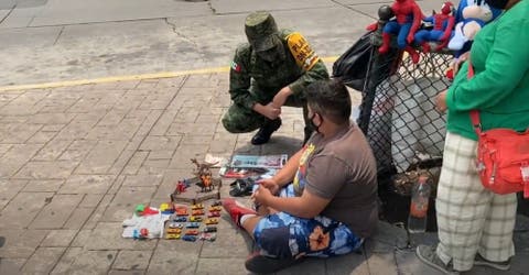 Los militares del ejército se acercan al niño que vende sus juguetes en la calle para comer
