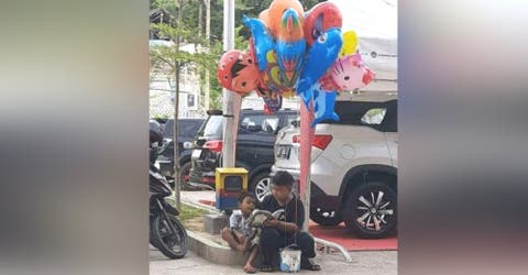 Un niño enseña a leer a su hermanito mientras sobreviven vendiendo globos en la calle