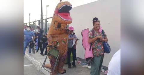 Aparece vestido de dinosaurio para alegrar a su madre que esperaría durante horas en una fila