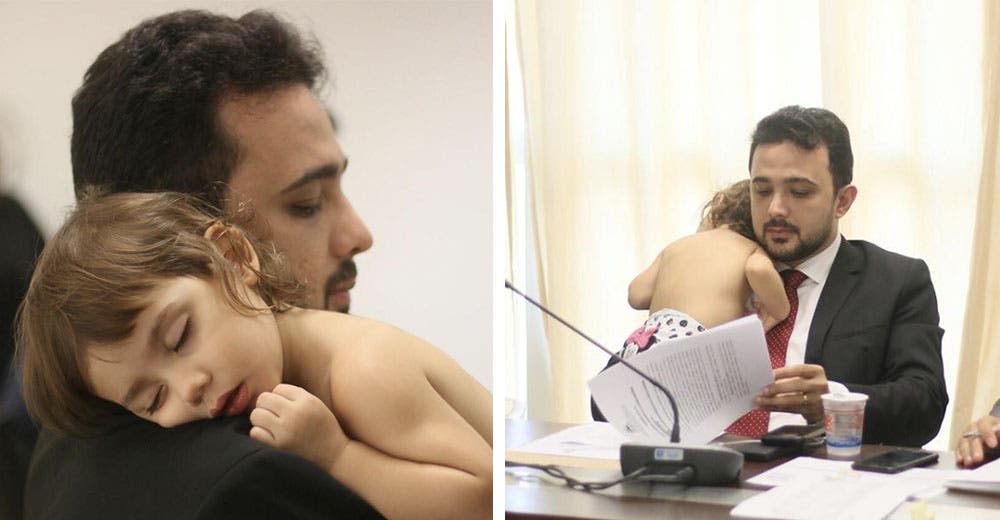 Un padre sostiene amorosamente a su hija en brazos durante una reunión de trabajo